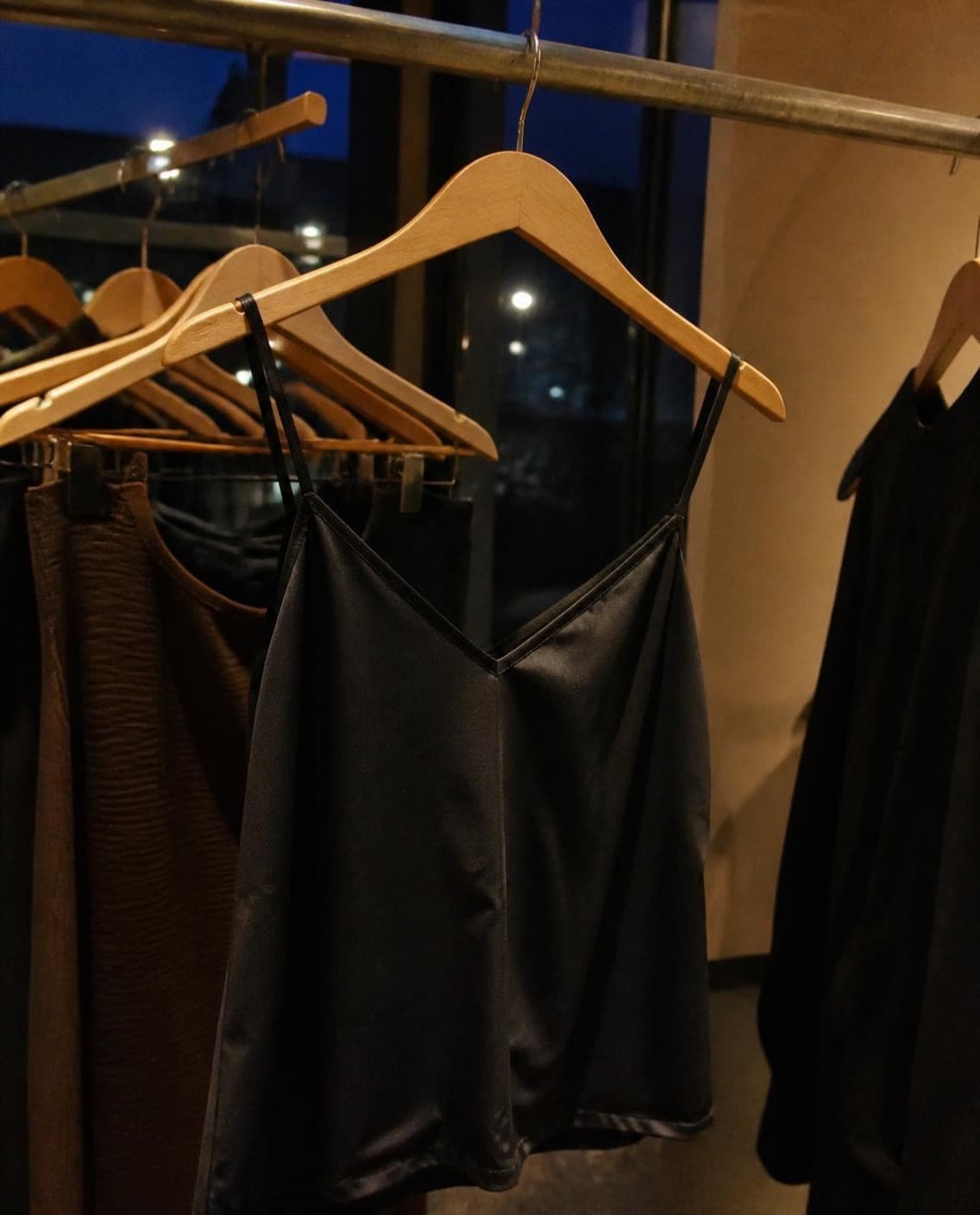 A black satin slip dress on a rail at night (a generated photo)