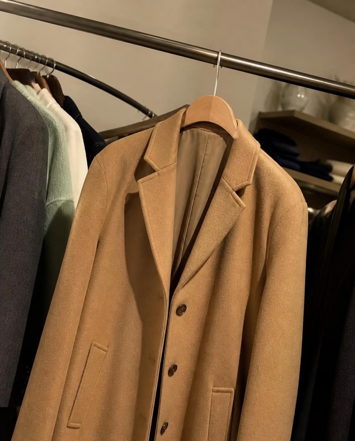A camel wool coat on a shop rail (a generated photo)