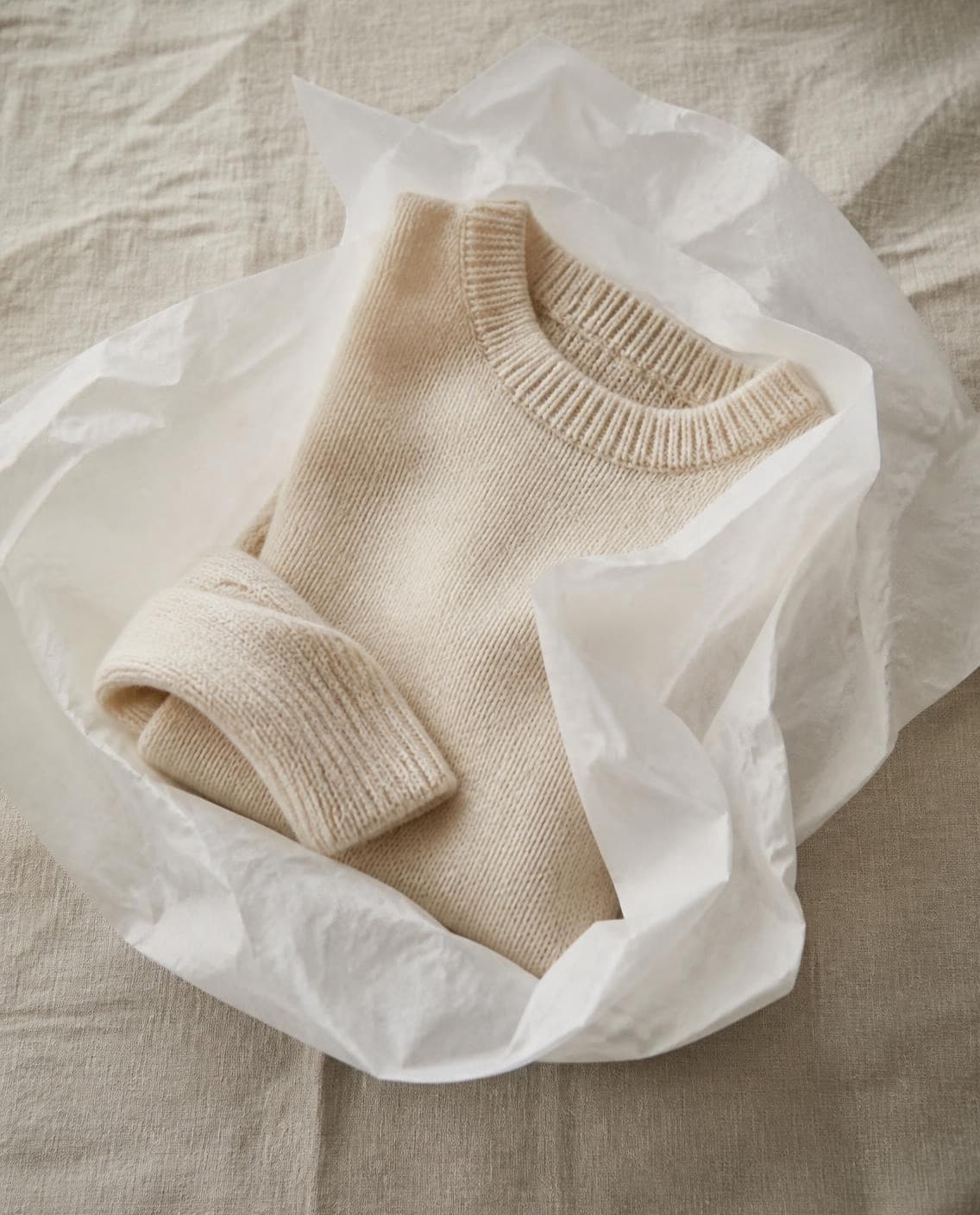 A cream knit folded in white tissue (a generated photo)