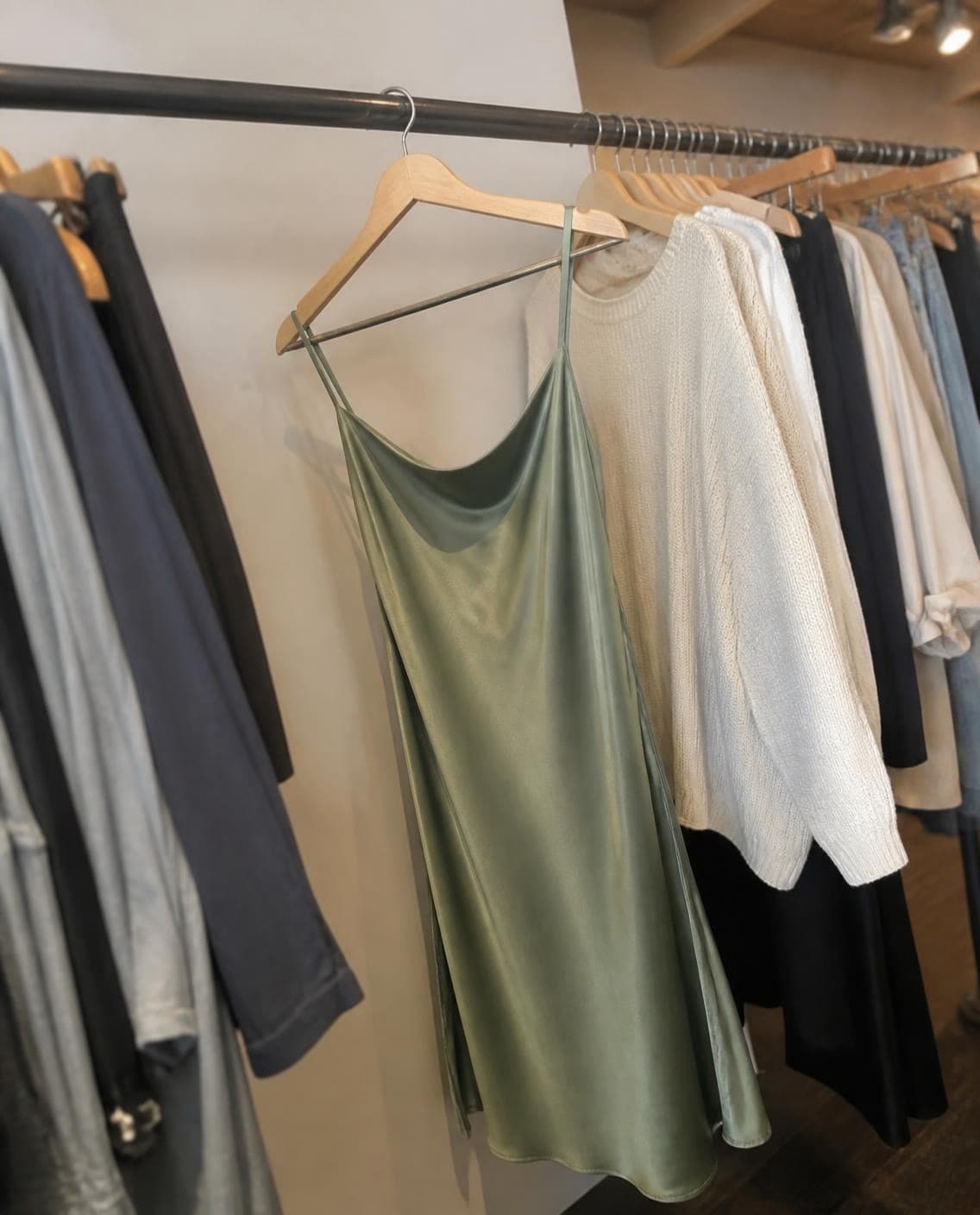 A sage satin slip dress on a shop rail (a generated photo)